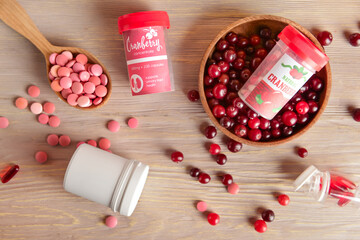 Healthy cranberry pills on wooden background