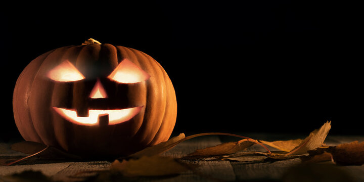 Halloween pumpkin head jack lantern with glowing eyes on wooden table