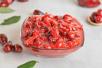 Bowl of delicious dogwood jam on light background