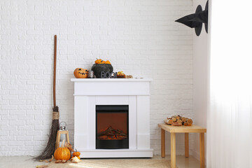 Modern fireplace with Halloween decor near white brick wall