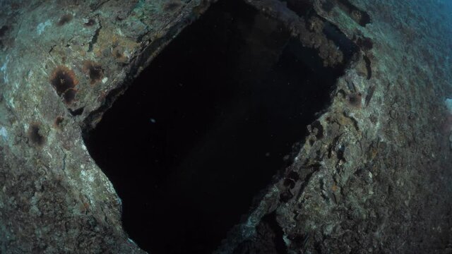 Unique scuba divers view entering a dark chamber inside a underwater shipwreck.