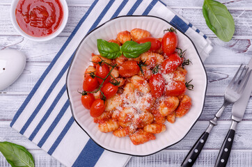 Gnocchi with tomatoes, red sauce, cheese and basil leaves