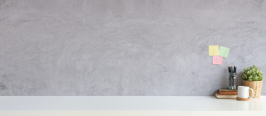 Empty picture frame, headphone, coffee cup and books on white table with loft wall. Copy space for your text message or information content.