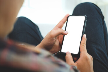 Casual man sitting on couch and using smart phone. Blank screen for your text message or information content.