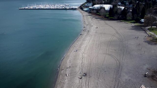 Flying over Jericho Beach shoreline over a sandy beach with Jericho Beach Sailing Club moorings in background
