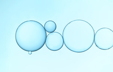 Closeup of water and oil droplets on light blue background.