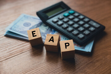 Selective focus of calculator, money and wooden cube written with alphabet EAP ( Employee Assistance Program ).