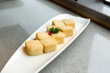 Silk tofu chinese tofu, soy cheese whole piece on ceramic plate over table in restaurant.