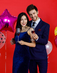 Businessman and businesswoman holding glass of drinks taking photo together in office afterwork party