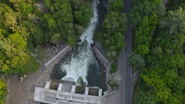Descending drone shot of a dam on a Canadian river in Ontario in summer with lots of whitewater flowing