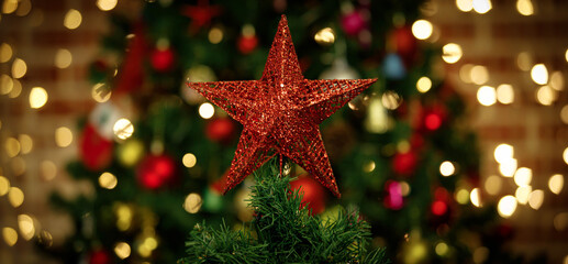 Close up shot of sparkling glossy glitter red star with cute Santa Claus decorating hanging dolls on top of green Christmas pine tree celebrating traditional festive night event on blurred background - Powered by Adobe