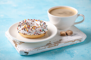 Fresh donut with cup of coffee on blue background