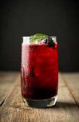 Blackberry cocktail with crushed ice on the rustic wooden background. Selective focus. Shallow depth of field.