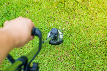 Hand Petrol lawnmower trimmer with motor cutting grass on a sunny summer day. Cutting grass in the garden. selective focus.