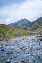 富山県立山町の立山の秋の紅葉の季節に登山している風景 Scenery of climbing Tateyama Mountain in Tateyama Town, Toyama Prefecture, Japan during the season of autumn leaves. 
