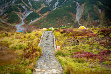 富山県立山町の立山の秋の紅葉の季節に登山している風景 Scenery of climbing Tateyama Mountain in Tateyama Town, Toyama Prefecture, Japan during the season of autumn leaves. 