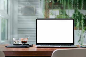 White screen laptop computer and supplies on wooden table in living room.