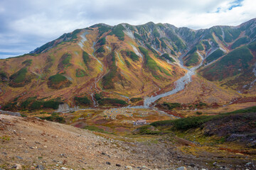 Fototapeta premium 富山県立山町の立山の秋の紅葉の季節に登山している風景 Scenery of climbing Tateyama Mountain in Tateyama Town, Toyama Prefecture, Japan during the season of autumn leaves. 