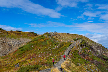 Fototapeta premium 富山県立山町の立山の秋の紅葉の季節に登山している風景 Scenery of climbing Tateyama Mountain in Tateyama Town, Toyama Prefecture, Japan during the season of autumn leaves. 