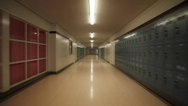 Cinematic establishing shot camera moving smoothly straight by the empty school corridor or hall with no students. B roll education in middle or high american school background footage during lessons