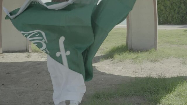 Child holding Saudi Arabia's flag and running 4K