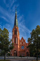 Fototapeta na wymiar Rot leuchtet die prachtvolle Fassade der Pauluskirche Berlin-Zehlendorf im frühen Morgenlicht (Blick von Südwesten)