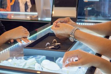 woman choosing diamond rings at jewelry store shop