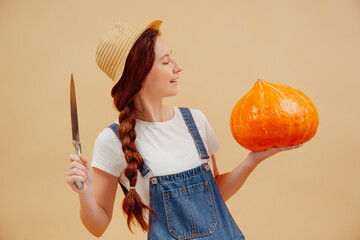 Woman in overalls with a sharp knife on a yellow background is going to cut a lantern out of a pumpkin. Concept of agriculture.