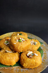 Indian traditional sweet balushahi served on a metal plate over black background. Also known as Balsaahi, badushah is a sweet food served on a Brass plate over moody background. Copy space.