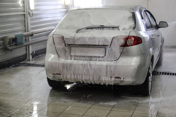 The car in the foam at the car wash box gets a full body cleaning.
