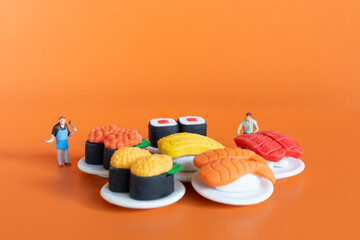Miniature people ,Chef making Sushi set on orange background