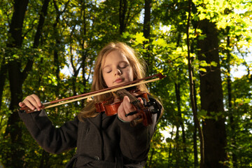 child plays the violin. play music. girl shouting on the violin in nature