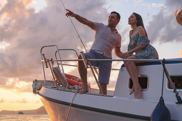Beautiful couple looking at sunset from the yacht