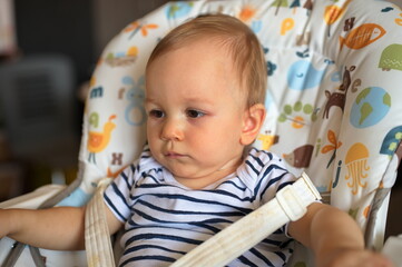 Adorable little baby sitting in high chair