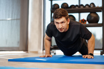 Fototapeta premium Young athletic man doing push-ups in a gym, close up
