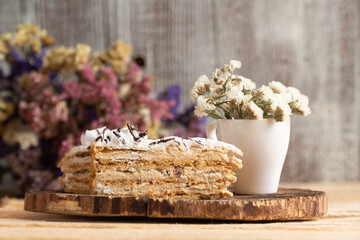A piece of mousse cake with a bouquet of flowers on the background
