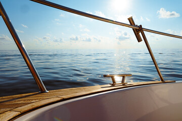 Deck of white yacht sailing in open sea at sunset