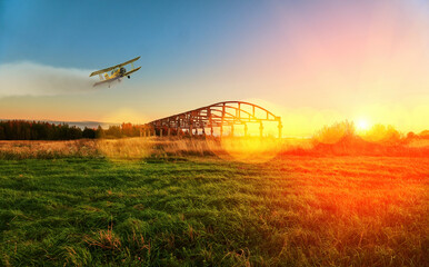 The landscape of the field, on the horizon you can see the old building and the forest. A plane flies in the sky, a corn man. Bright sun shines through tree branches, agriculture