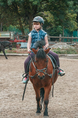 Little girl goes in for equestrian sports. The child is riding a horse.