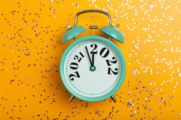 New Year 2022 background concept. 2021 changes to 2022 on an alarm clock on a yellow background...
