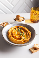 Bowl with pumpkin hummus, delicious appetizer decorated with greens and spices