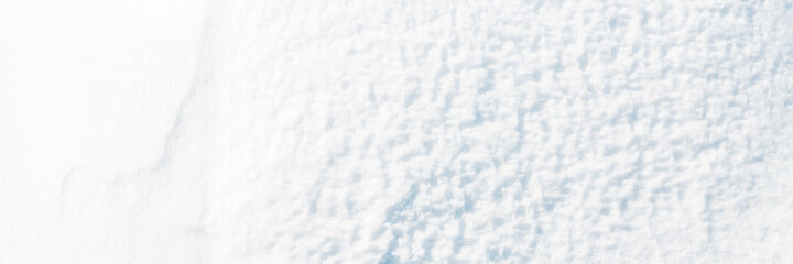 Beautiful winter background with snowy ground. Natural snow texture. Wind sculpted patterns on snow surface. Wide panoramic texture for background and design.