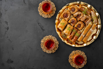 Turkish tea in traditional glasses baklava on black background