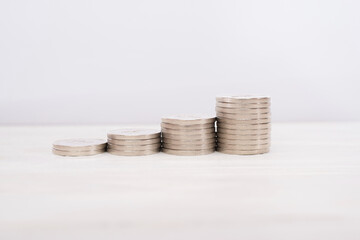 Rising stacks of coins on a white wooden background.