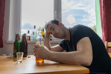 young male man sit next to table drink alcohol bottle at home sad alone alcoholism Signs and...