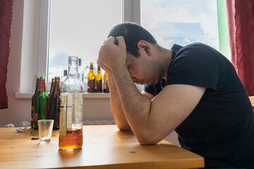 young male man sit next to table drink alcohol bottle at home sad alone alcoholism Signs and...