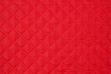 Quilted fabric. The texture of the blanket. Red textiles
