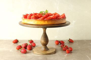 Wooden stand with strawberry tart on gray textured table