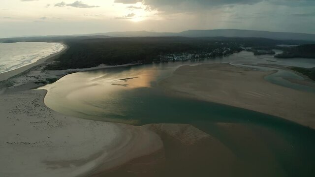 Aerial drone footage of inlet at Cunjurong Point at sunset reflected in water down the south coast of Australia near the town of Cunjurong Point surrounded by the Conjola National Park