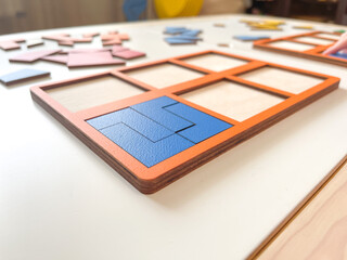 The child collects puzzles. Educational wooden toy for learning. Montessori materials. Fine motor skills, hand-eye coordination. Children's leisure, nursery.The concept of early development. squares. 